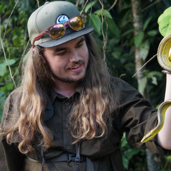 Mikkel Sortemos fra Arternes Verden står med en slange i hånden. Mikkel kigger på slangen, som har en gul bug.