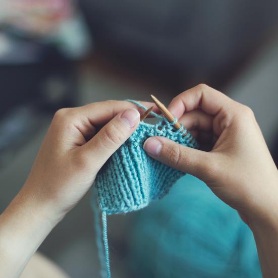 Et par hænder sidder med et strikketøj