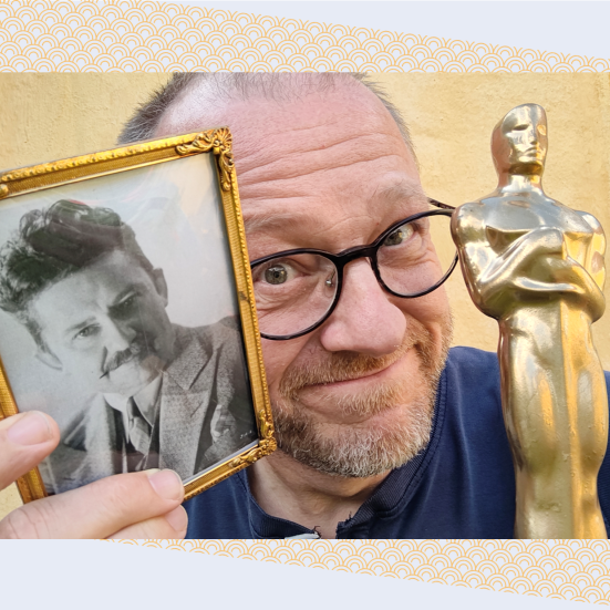 Hans Wendelboe Bøcher står med et foto af Jean Hersholt og en Oscar-statuette