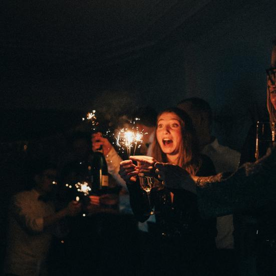 En gruppe mennesker står med champagne og stjernekastere. Det ligner en nytårsfest.