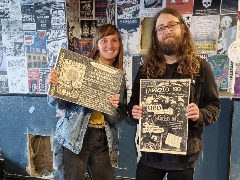 Matilde og Tobias Aske holder en plakat hver foran sig. Man kan se deres ansigter, og at de smiler. Billederne er taget på 1000Fryd, hvor væggene er dækket af plakater.