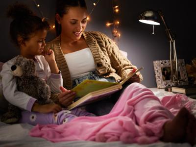 Mor og barn sidder i seng og læser 