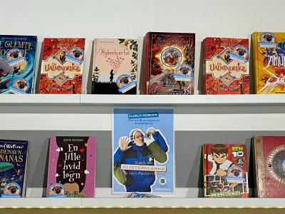 En udstilling med mange bøger med forsiden udad. Det er børnebøger, som har klistermærker på med teksten "Brandvarm anbefaling".
