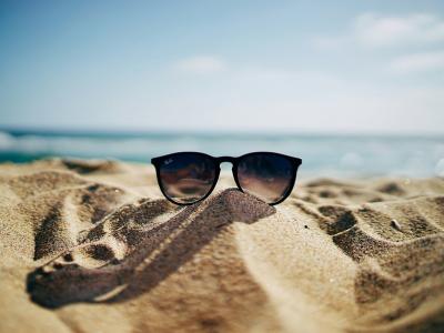 Billede af solbriller på sandstrand. Foto: Ethan Robertson, Unsplash.