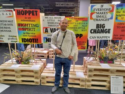 En mand står foran paller med skilte på, hvor der blandt andet står "Big change" og "Fighting spirit"