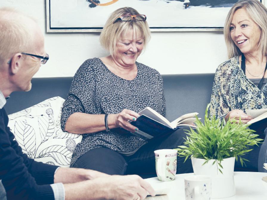 Foto af tre personer, der diskuterer en bog