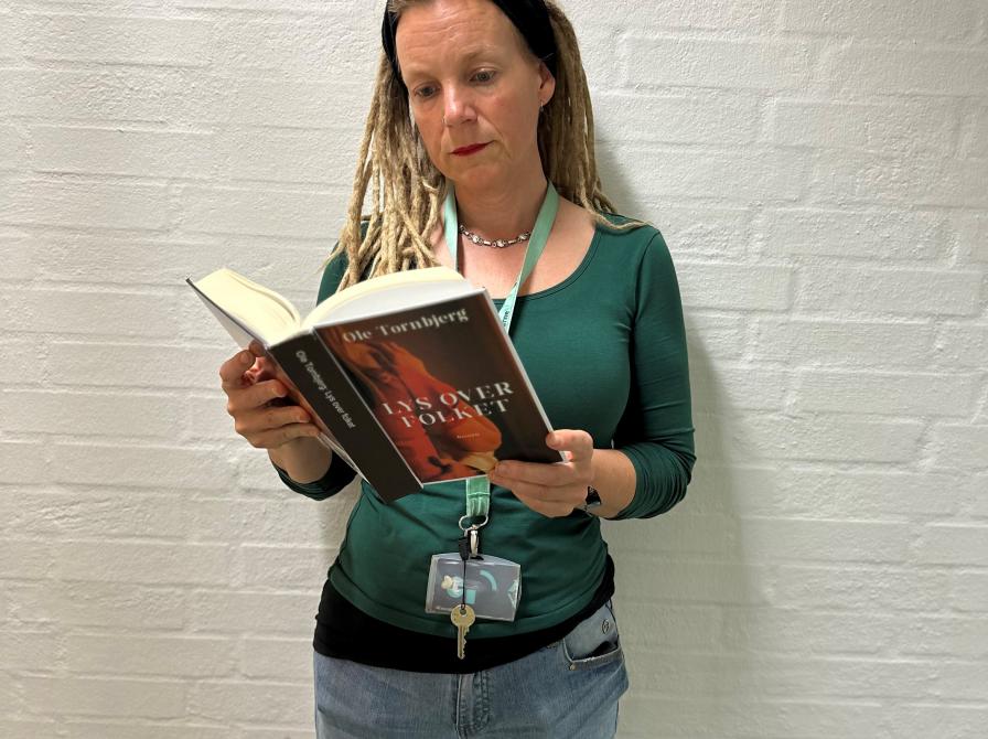 Karina står på kontoret på Hovedbiblioteket og læser i bogen "Lys over folket".