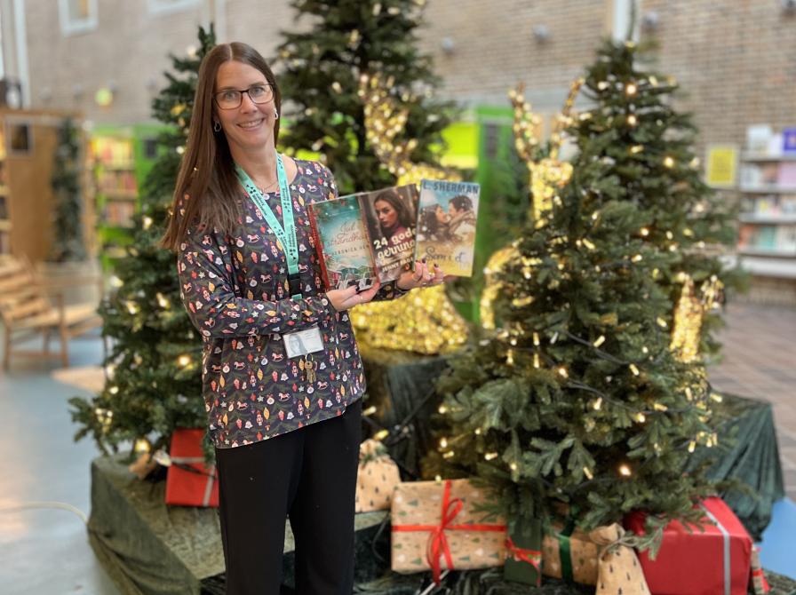 Line står foran juleudstilling på Hovedbiblioteket med tre af de omtalte bøger i hænderne.